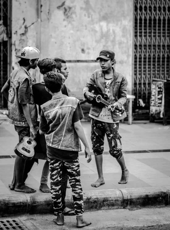 black and white po of boys playing guitars on the street