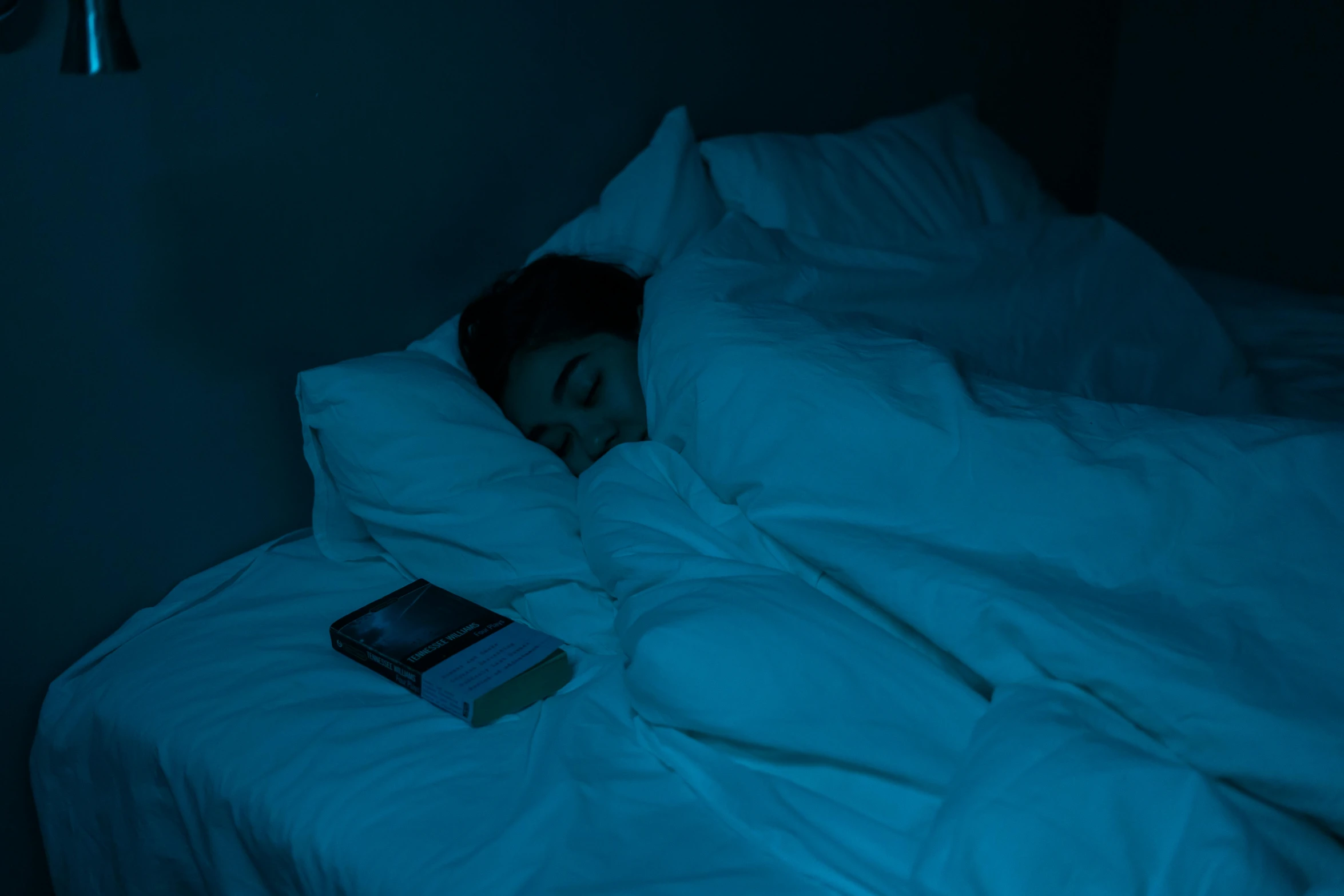 a woman sleeping on top of a bed under a blanket