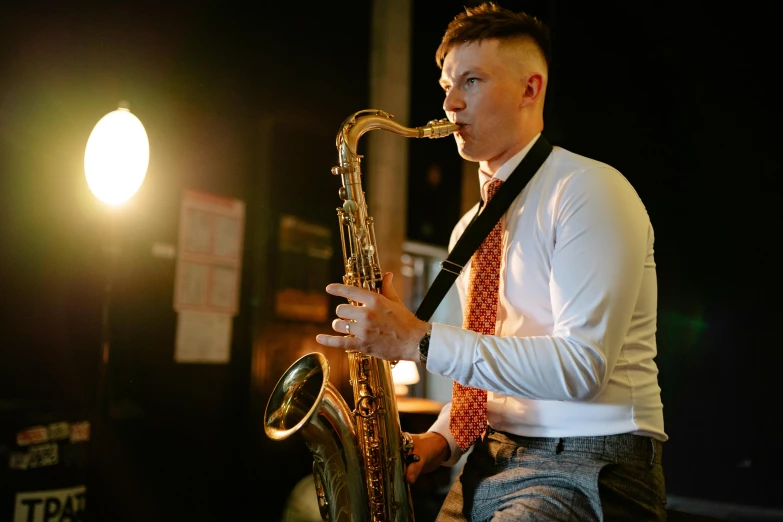 a man playing a saxophone at night, with light behind him
