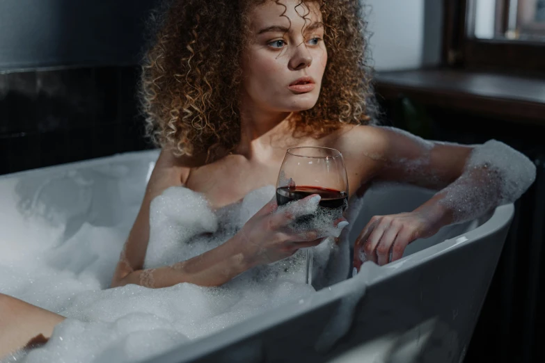 woman sitting in bubble bath with a wine glass