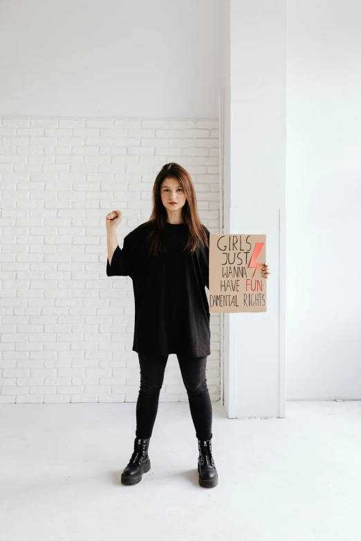 a woman standing next to a brick wall with her fist raised