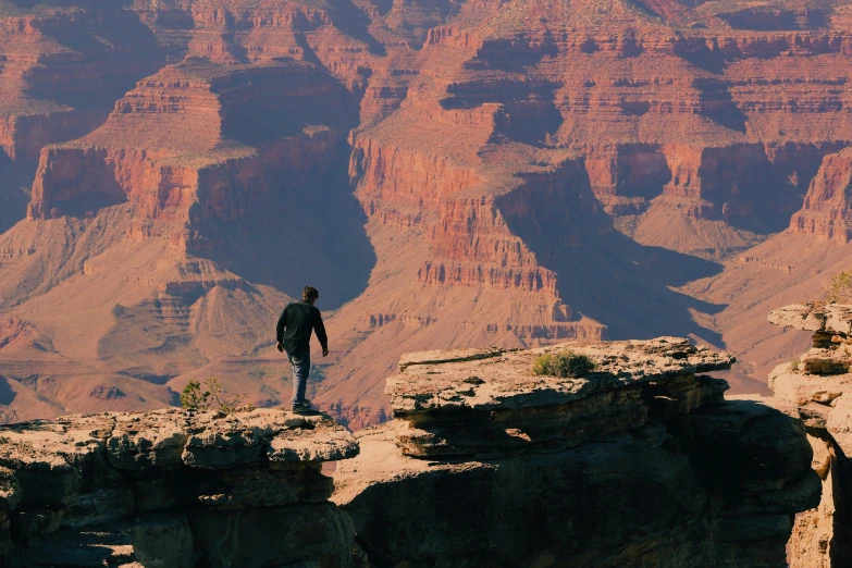 person stands at the edge of a cliff overlooking a mountain