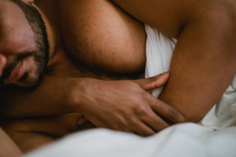 a man sleeping in bed while clutching his arm