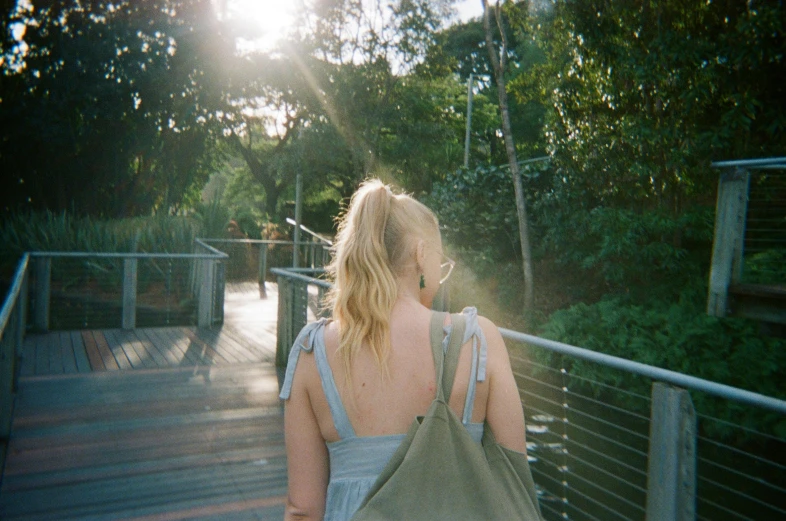 a woman with a bag walking up a wooden path