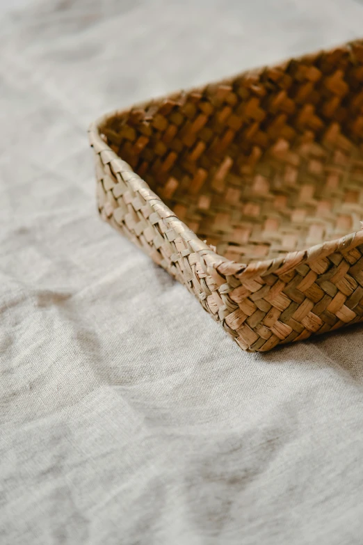 a small woven basket that is on a white blanket