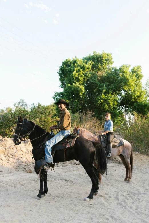 two men are riding horses in the sand
