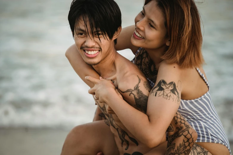 two people that are hugging and smiling on a beach