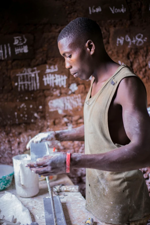 a man in a white shirt making dough with knife and spatula