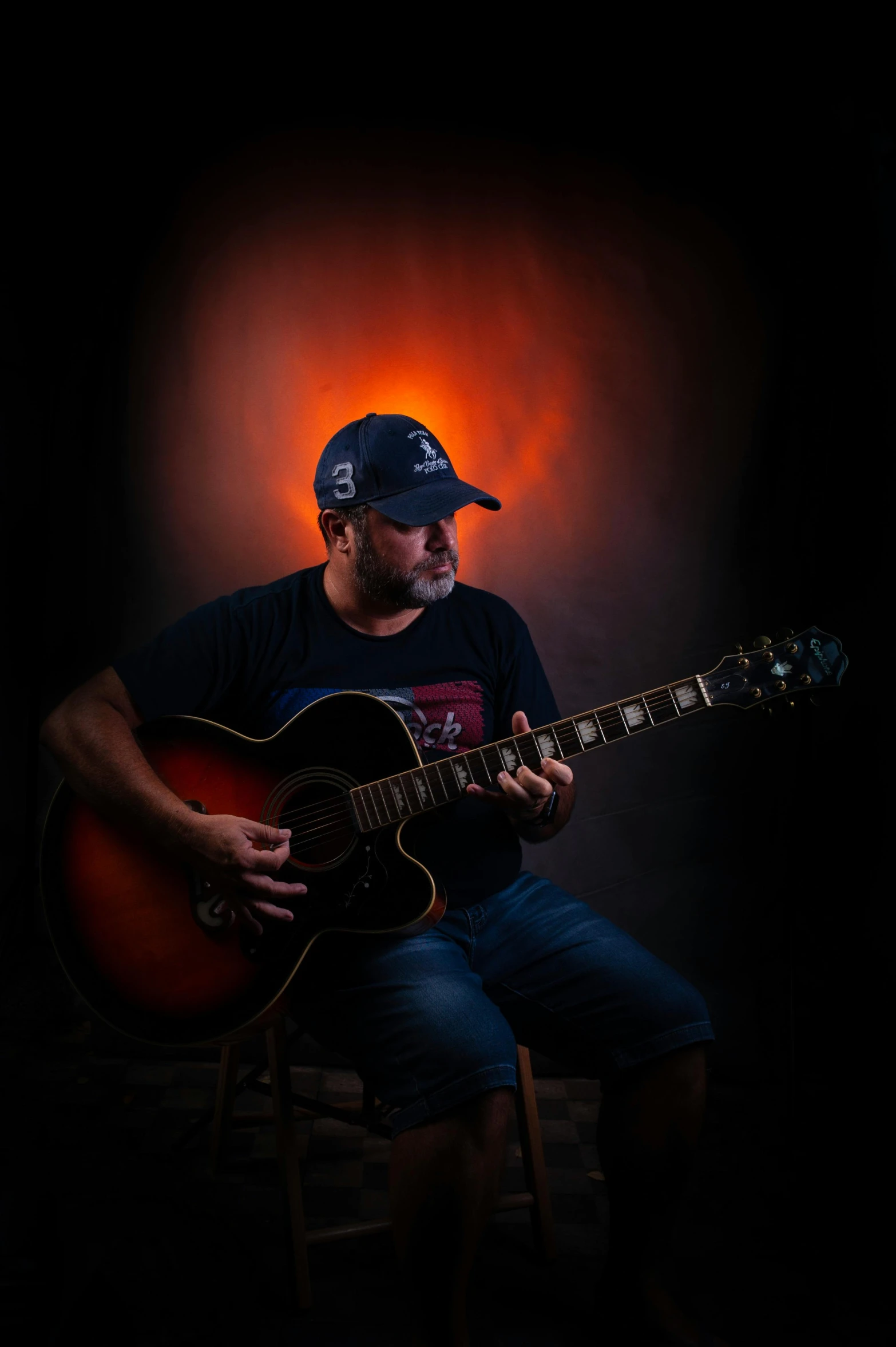 a man sits with an acoustic guitar in his hands