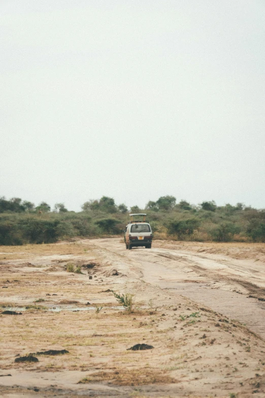 a van is driving down the dirt road