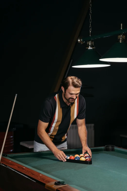 a man standing over a pool table with balls on it