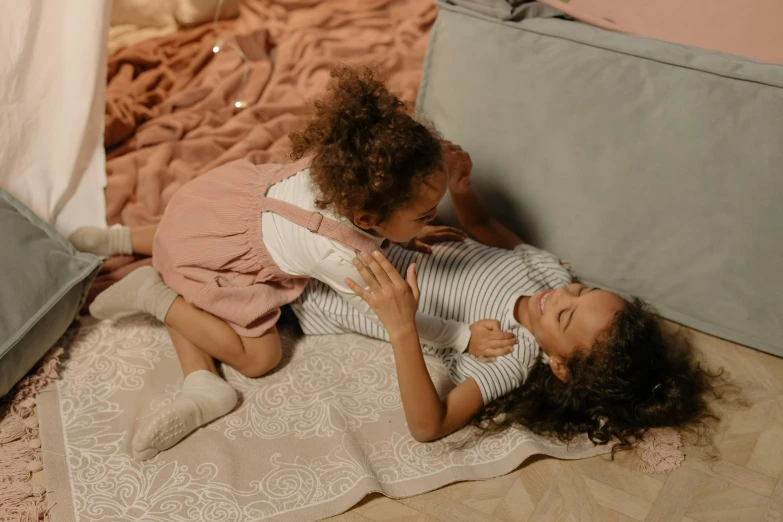 two small children laying on a white blanket on a bed