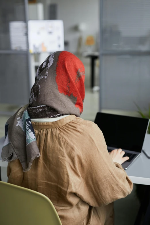 a person with a hood on sitting in front of a computer