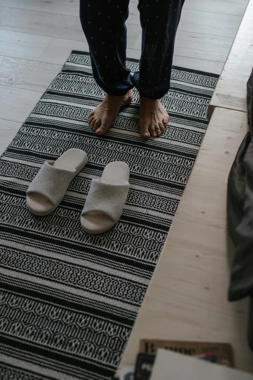 someone wearing sandals standing on a rug by the door