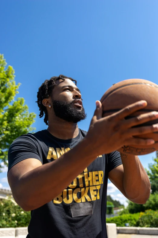 the man holds a basketball up to his eye