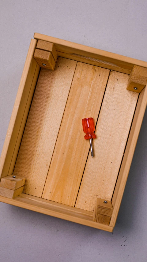 a red pen is placed in a square wooden box