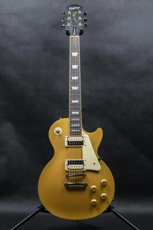 an electric guitar that is yellow with gold hardware