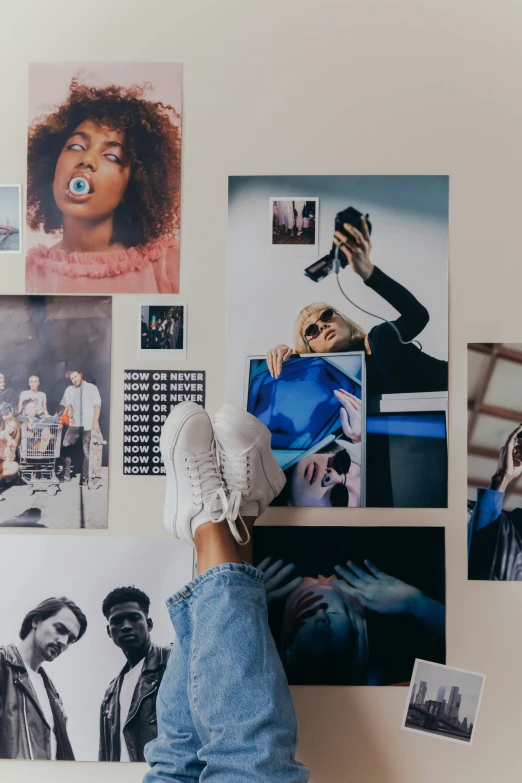 a person's feet up on a wall with various pictures and posters