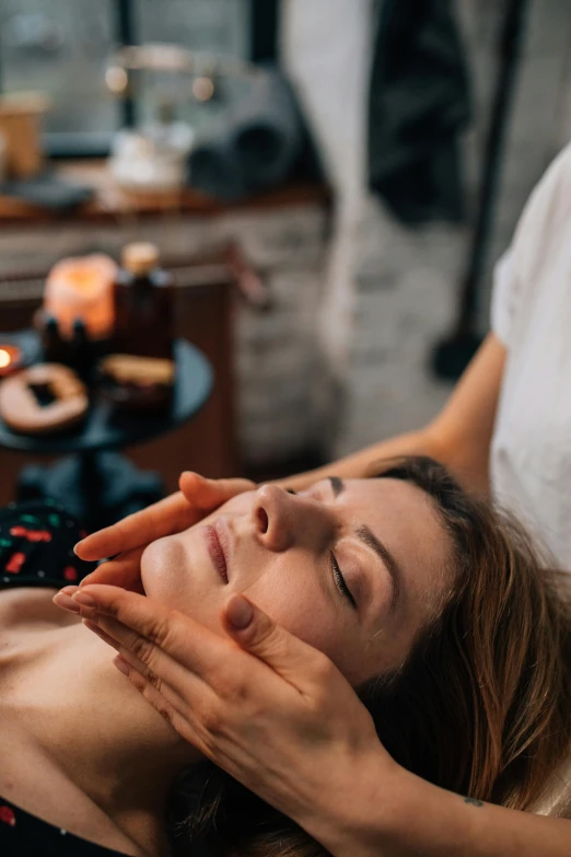 a woman receiving facial peel massage with candles