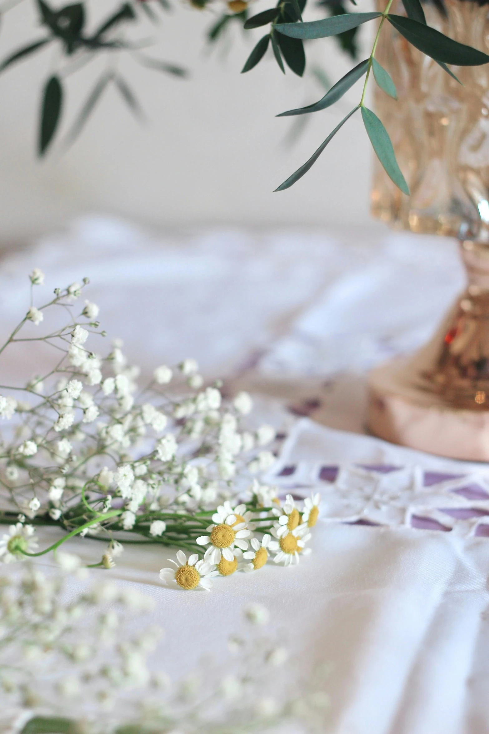 vases of flowers sitting on a lace covered tablecloth