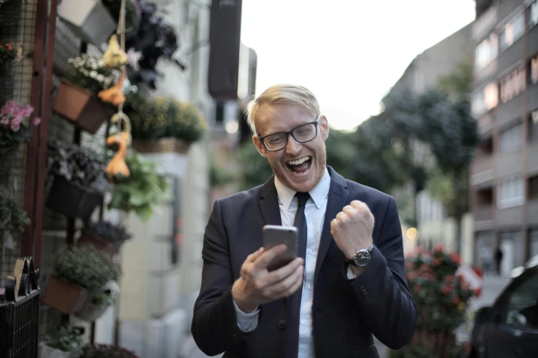 an older man in a suit and glasses uses his cell phone