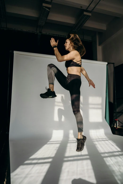 woman wearing black and white patterned leggings, with a shadow on the wall