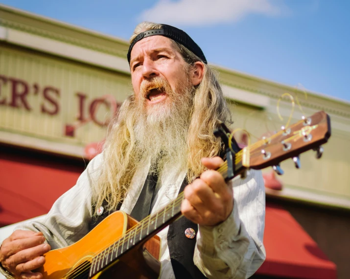 a bearded man in a top hat playing a guitar