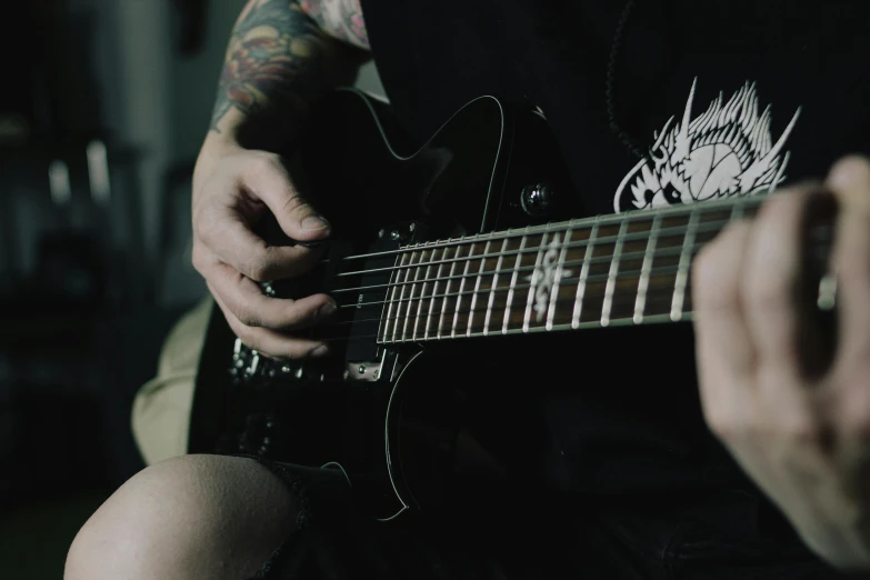 tattooed man playing guitar close up black and white po