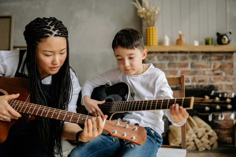 two children playing a guitar while an adult plays one