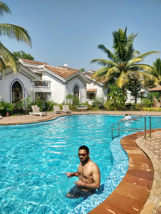 a man holding his hand up to the water in an open swimming pool