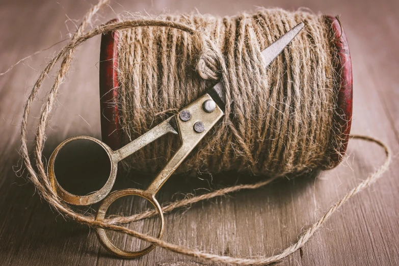 spools of string next to pair of scissors on wood table