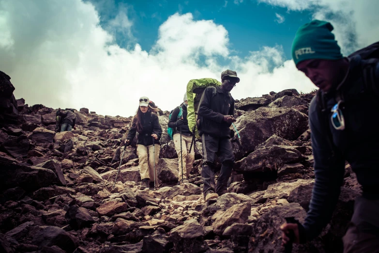 several men hike up a rocky hillside during the day