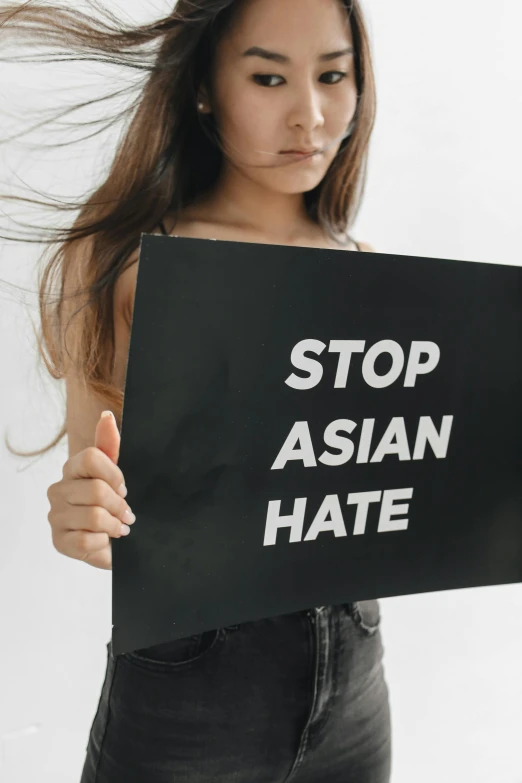 asian woman showing sign that says stop asian hate