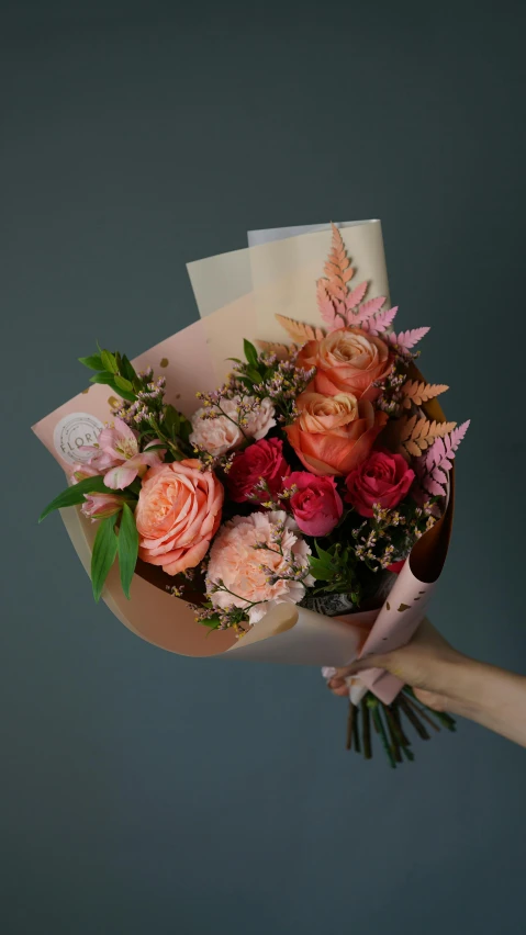 a hand holds flowers with pink and red colors