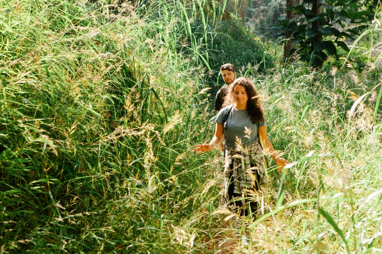 a man and woman walking through some tall grass