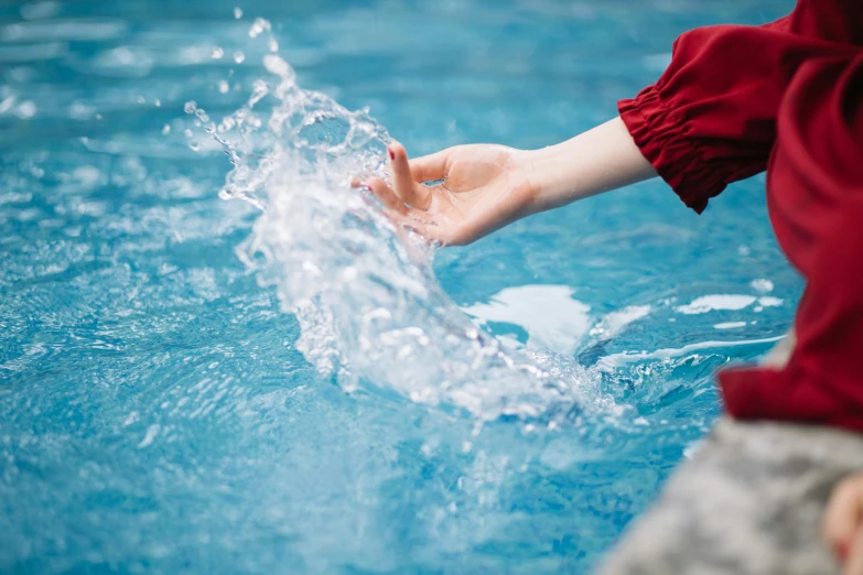 a person holding their hand out towards the water