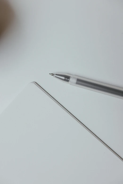 a silver pen with a long pointed tip resting on top of a piece of paper