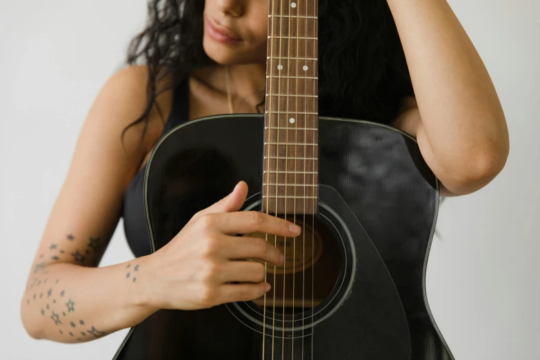 woman holding a black acoustic guitar in her hands