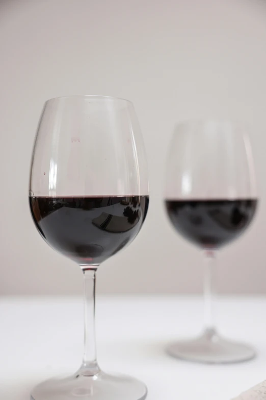 two wine glasses with different colored wine sitting side by side