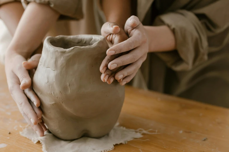 a woman making a pottery vase on a table