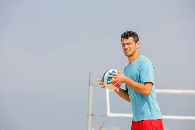 a man holding a volleyball on top of a field