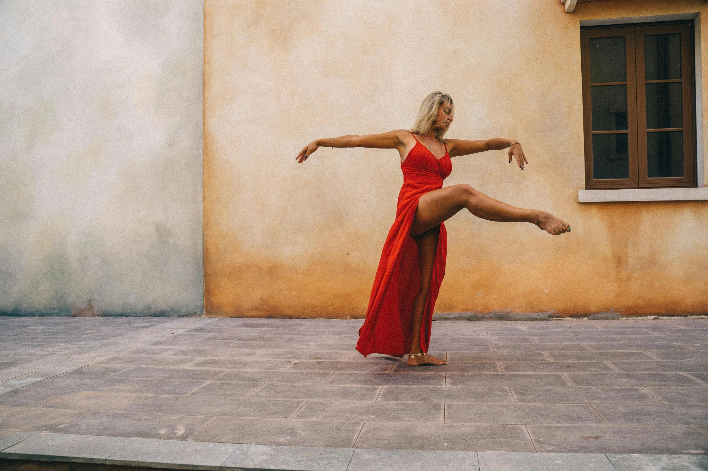a woman dancing on the ground wearing a red dress
