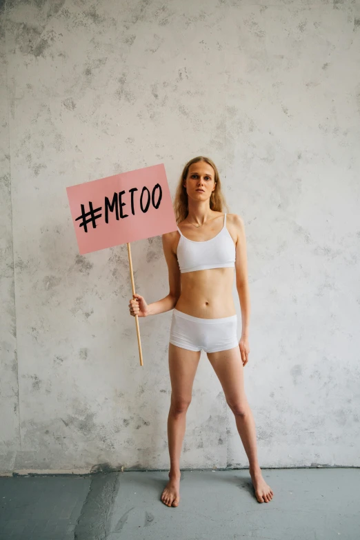 woman in underwear holding up a sign that reads meto