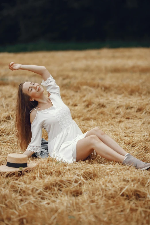 a woman is sitting in a field with her  wide out and stretching