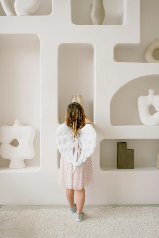 a girl looking over a wall of shelves with vases on them