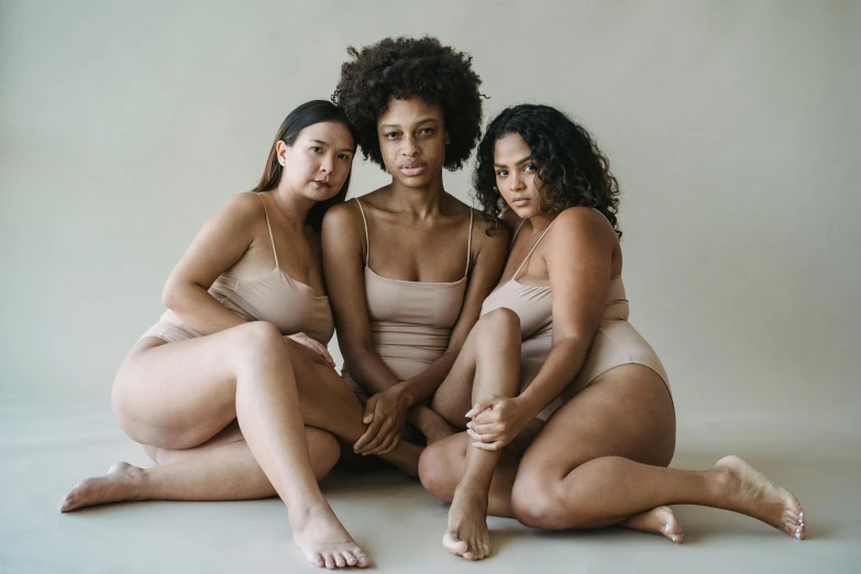 three women sitting down on the ground in tight clothing