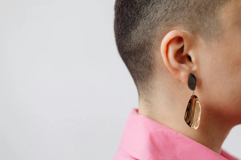 the back of a woman's head with two earrings hanging from it