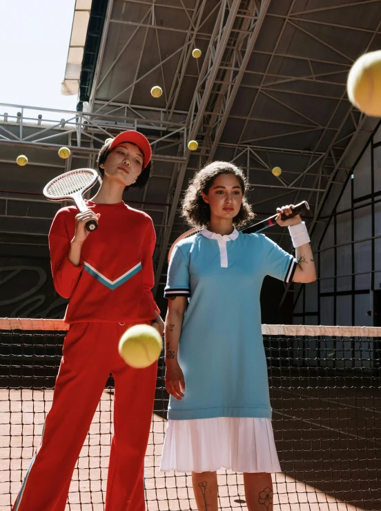 a boy and girl standing by tennis court with rackets