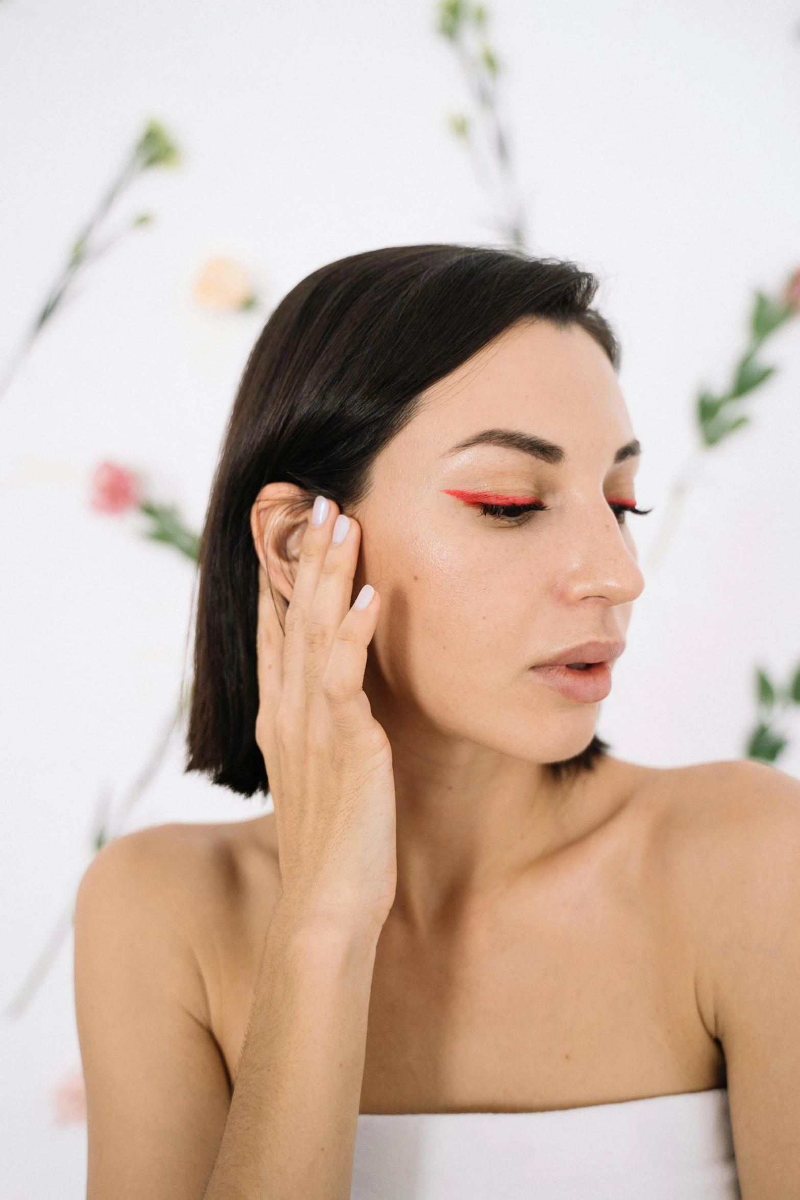 a woman with dark hair is holding her ear