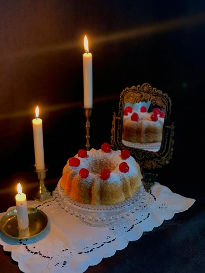 two small cakes are on a table in front of a candle and a mirror